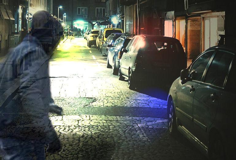 grafika przedstawia ulicę w nocy z zaparkowanymi samochodami oraz pojawiający się cień złodzieja w kapturze